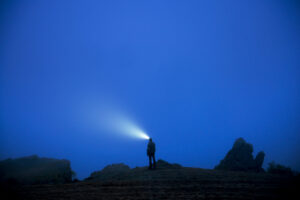 Man on rocks in at dusk with headlamp